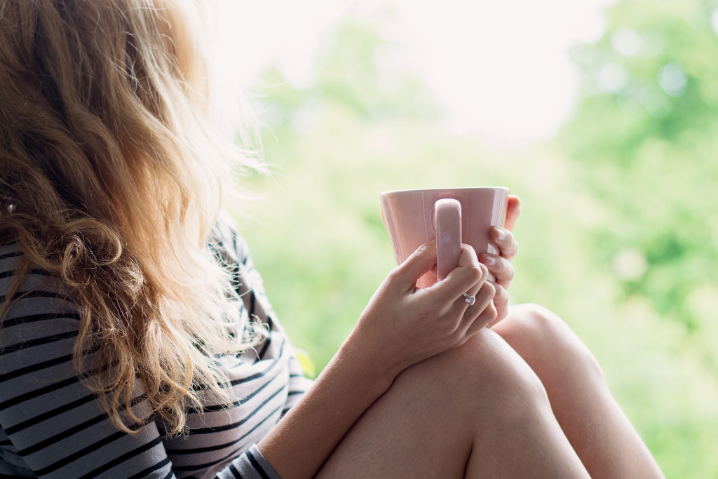 Peaceful woman relaxing at home with cup of tea or coffee