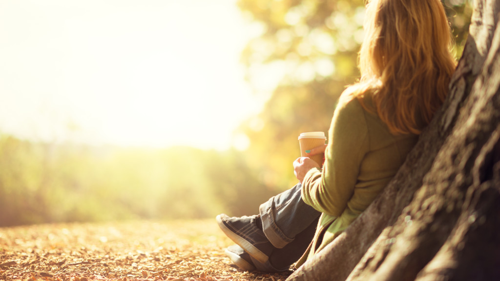Autumn concept, anonymous woman enjoying takeaway coffee cup on sunny cols fall day